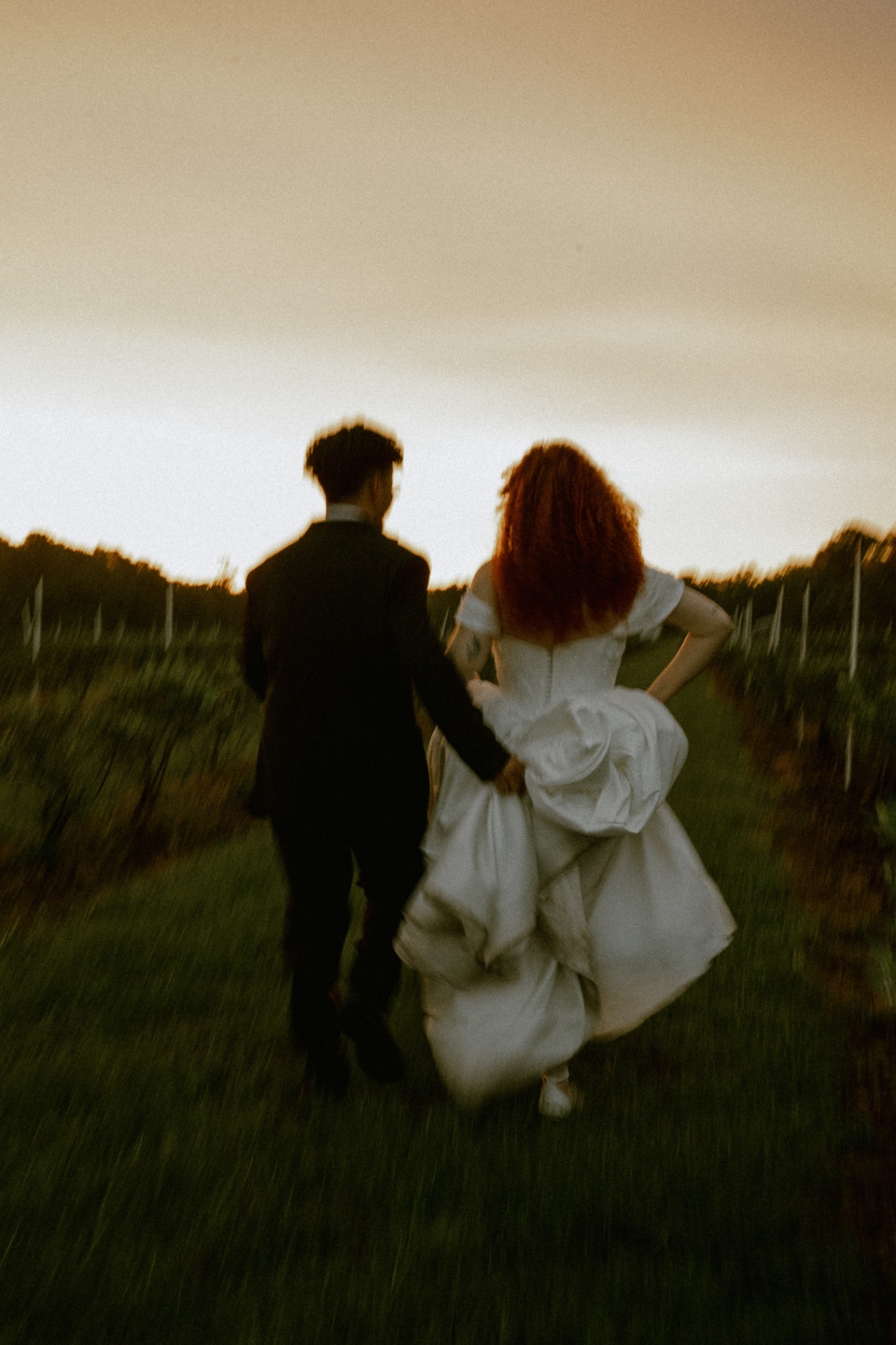 Lily and Alephe running through a vineyard at sunset